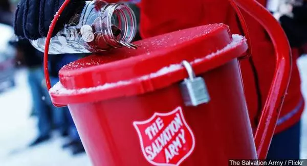 Coin jar being tipped into red plastic kettle