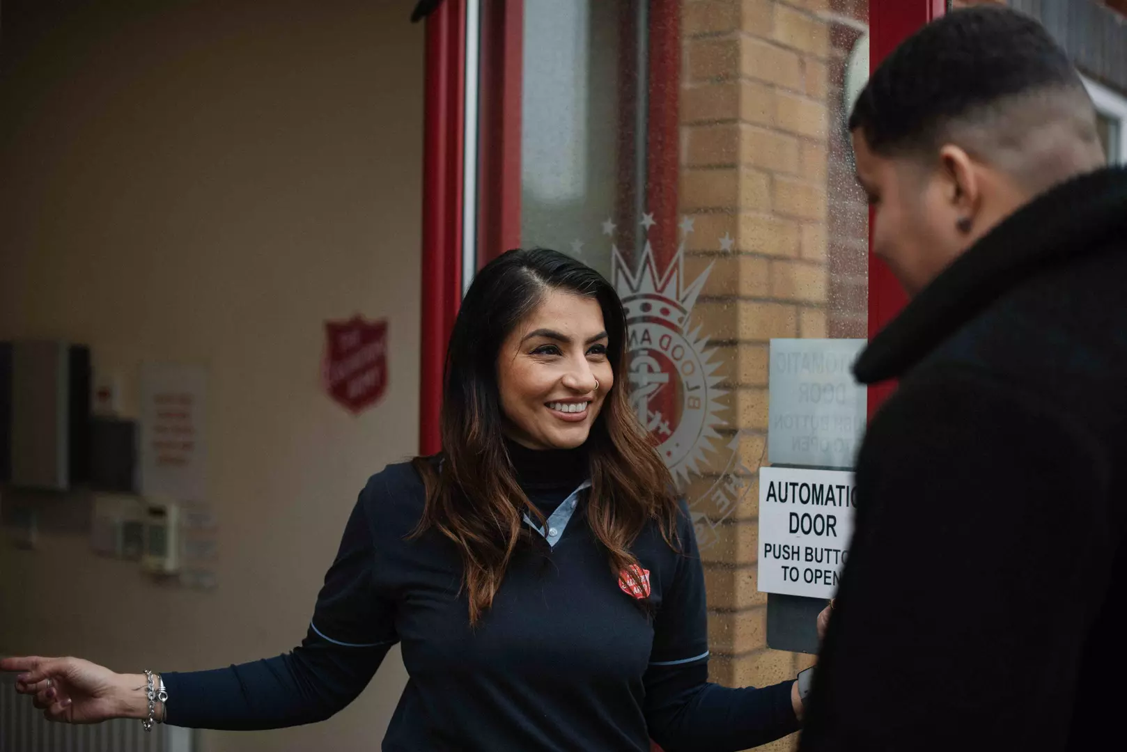 A Salvation Army female officer holding the door open for a man