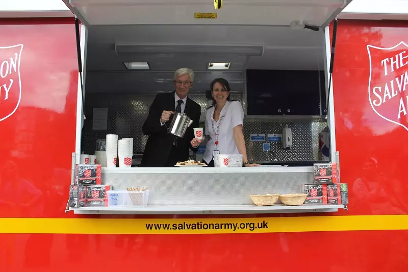 Paul O'Grady posing with Salvation Army Officer Captain Jo Moir with a cup of tea in one of our emergency response vehicles. 