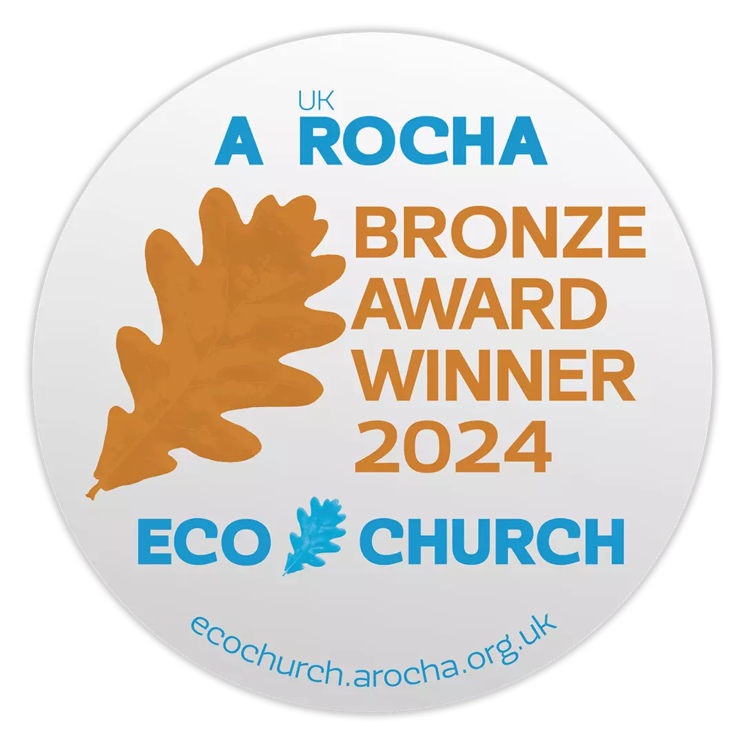 A white button with a bronze leaf and text saying: Bronze Award Winner 2024. UK A Rocha Eco Church.